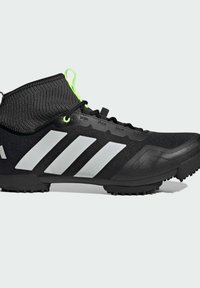 Chaussure de sport noire avec une tige en tissu texturé et un col style chaussette. Présente trois rayures blanches et des lacets réfléchissants verts. Semelle extérieure en caoutchouc pour l'adhérence.