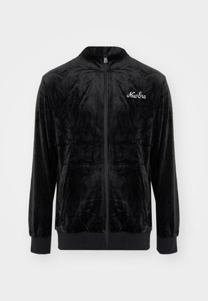 Schwarze Samt-Zip-Jacke mit hohem Kragen, gerippten Bündchen und Taille. Mit weißem "New Era"-Logo auf der linken Brust. Weiche Textur.