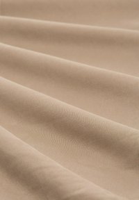 Beiger Stoff mit einer glatten Textur, der weiche Falten und ein mattes Finish aufweist, und eine gleichmäßige Farbe ohne Muster oder Akzente zeigt.