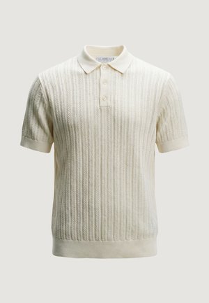 Polo a maniche corte in maglia color crema con motivo a trecce verticali testurizzate e abbottonatura a tre bottoni su sfondo uniforme.