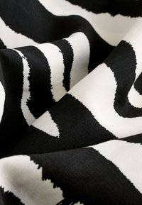 Black and white fabric with zebra stripe pattern, featuring crisp edges and a smooth texture, displayed in folded layers.