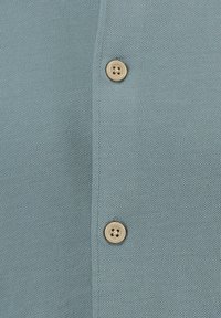 Cardigan lavorato a maglia di colore azzurro chiaro con una superficie liscia e due bottoni tondi beige. Il tessuto presenta un fine e uniforme motivo a maglia.