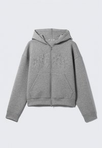 Šedá mikina s kapucí na zip vyrobená z fleecu, obsahující kapuci, klokaní kapsy a vystouplý design na hrudi. Měkká textura s žebrovanými manžetami.