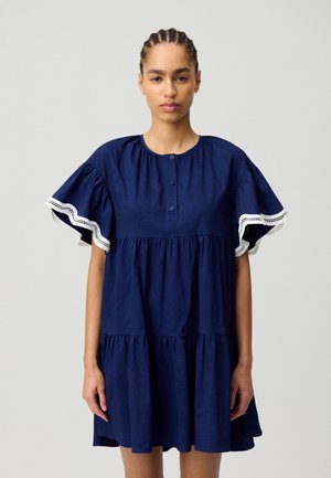 Vestido de algodón azul marino con mangas cortas acampanadas, tapeta de botones, diseño en capas y borde de encaje blanco en los bordes de las mangas.