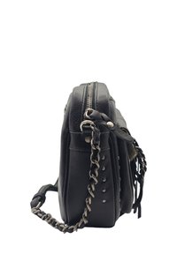 Sac bandoulière en cuir noir avec des détails en clous argentés, fermeture éclair supérieure et bandoulière tressée, présenté en vue de côté sur fond blanc.