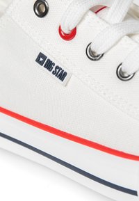 Weißes Canvas-Sneaker mit roten Akzenten, ausgestattet mit runden Metallösen, weißen Schnürsenkeln und einem "BIG STAR"-Tag an der Seite. Gummisohle.