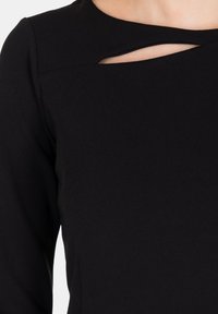 Abito nero a maniche lunghe con scollo a barca, caratterizzato da un dettaglio distintivo con ritaglio sul petto. Realizzato in tessuto liscio, offre una silhouette aderente.