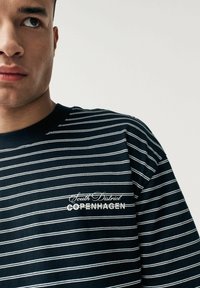 Marineblå bomulds t-shirt med hvide vandrette striber og grafisk tekstprint, der står "South District COPENHAGEN."