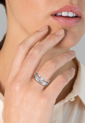 Anillos de plata que presentan tres bandas apiladas con un acabado pulido. Una de las bandas cuenta con un acento de gema central, añadiendo detalle al diseño.