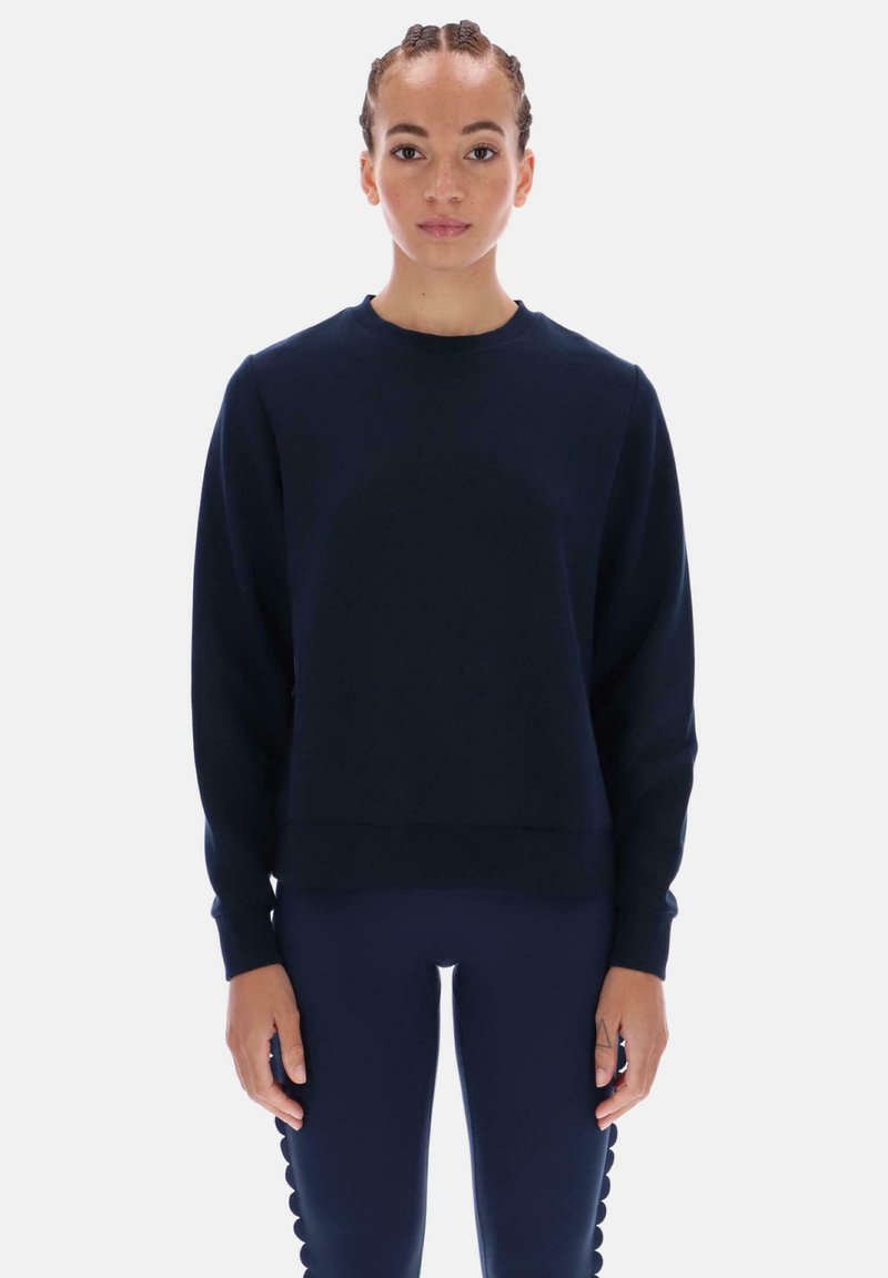 Laivastonsininen collegepaita pyöreällä pääntiellä ja resorituhansapuilla, tehty pehmeästä kankaasta. Yhdistetty saman sävyisiin, istuviin leggingsseihin, joissa on aaltoilevia yksityiskohtia.