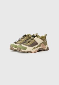 Green and beige outdoor shoes with a textured surface, featuring a rounded toe, lacing system, and patterned mesh panels. Rubber sole.