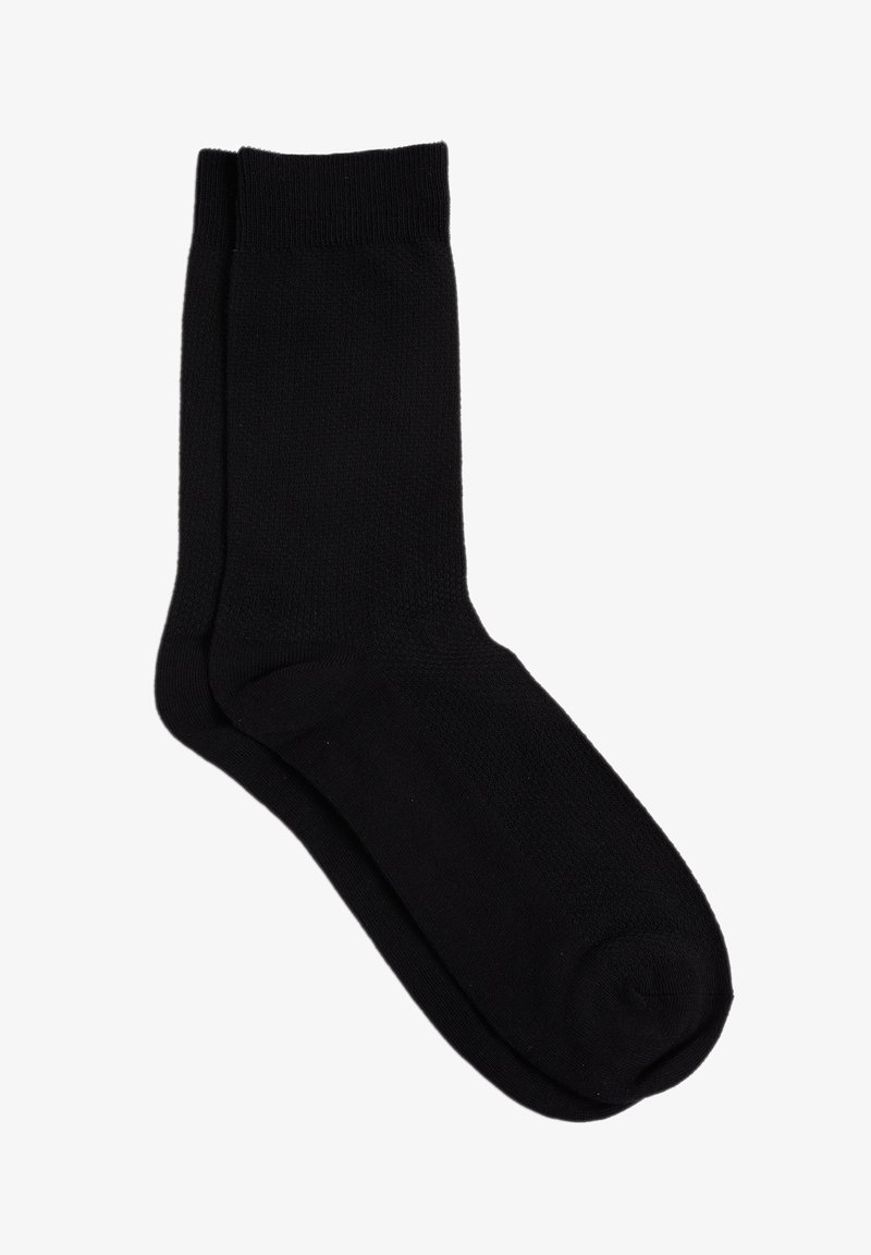 Čierna bavlnená ponožka s hladkou textúrou, dĺžka po stred lýtka a základným dizajnom, ktorý obsahuje rebrovaný manžetový okraj a vystužené špičky a päty.