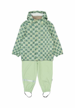 Groene geruite regenjas met capuchon, met diverse kleine patronen, gecombineerd met bijpassende lichtgroene broek en reflecterende accenten.