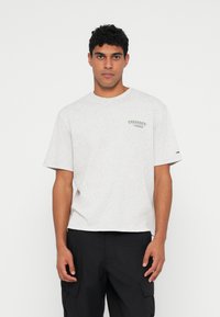 Grå bomull T-skjorte med rund hals, kortermet, og grønn logo trykk på venstre bryst. Har en avslappet passform og myk tekstur.