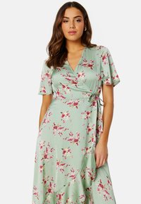 Kwiecista sukienka w odcieniu miętowym, wykonana z materiału, charakteryzująca się krótkimi rękawami, dekoltem w kształcie V oraz różowymi i żółtymi wzorami kwiatowymi z zaznaczeniem w talii.