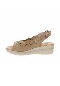 Sandalo slingback in pelle beige con design perforato, punta aperta, soletta bassa a cuneo e soletta testurizzata per un comfort aggiuntivo.
