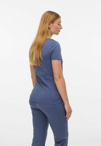 T-shirt bleu à manches courtes en tissu doux, avec un col rond et une coupe décontractée, porté avec un pantalon assorti.