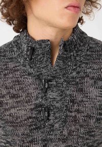 Suéter de punto texturizado en gris oscuro, con cuello alzado y tres botones de toggles negros para el cierre.