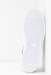 Semelle blanche de basket avec motifs de bande de roulement carrés et ondulés, et logo Puma au centre.