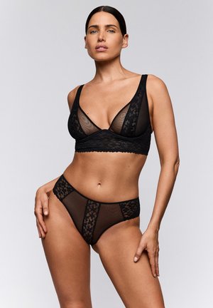 Zwart lingeriesetje met een kanten bralette met mesh inzetstukken en hoog uitgesneden slip met kanten panelen, met ingewikkelde patronen en texturen.