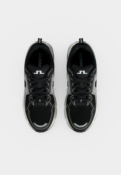 Paire de chaussures de sport noires et grises avec des accents et des lacets blancs, vues de dessus sur fond blanc.