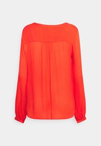 Blouse rouge à manches longues en tissu léger. Présente un col rond, des détails froncés au dos et des poignets boutonnés. Texture lisse.