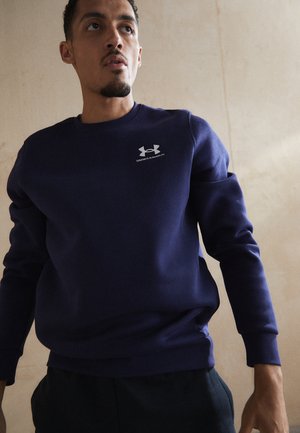 Marineblå sweatshirt med lange ærmer, rund hals og ribbede manchetter. Har et sølvlogo på brystet. Blød stofstruktur.