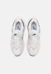 Nike sneakers feature a mesh and synthetic upper in white, with gray accents, a pink midsole, and a durable black outsole.