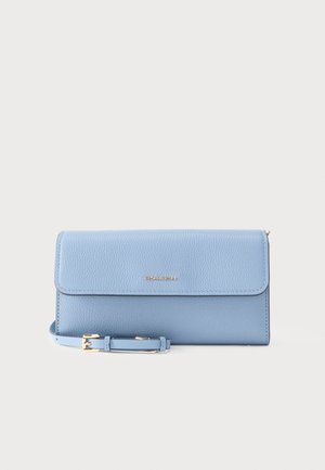 Lichtblauwe clutch van geborsteld leer met goudkleurig "Michael Kors"-logo en een verstelbare riem met een gouden gesp, geplaatst tegen een effen achtergrond.