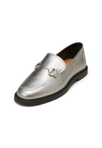 Mocassin en cuir argenté avec semelle noire et détail en métal à l’avant, incliné vers la gauche avec intérieur beige visible.