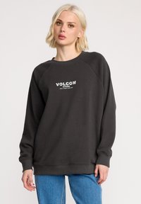 Donkergrijze sweatshirt met een ronde halslijn, raglanmouwen en een witte "VOLCOM STONE"-logo aan de voorkant. Zacht materiaal, ontspannen pasvorm.