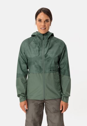 Giacca impermeabile verde con cappuccio, caratterizzata da una chiusura con zip, un design bicolore, polsini elasticizzati e un logo sul lato sinistro in basso.