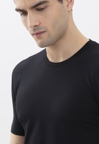 T-shirt nera a maniche corte realizzata in tessuto morbido e liscio, con scollatura rotonda e silhouette aderente, mostrata su uno sfondo neutro.