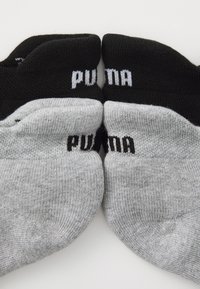 Chaussettes de cheville noires et grises, avec des bords côtelés et un marquage contrastant. Matériau doux et extensible avec une texture lisse.