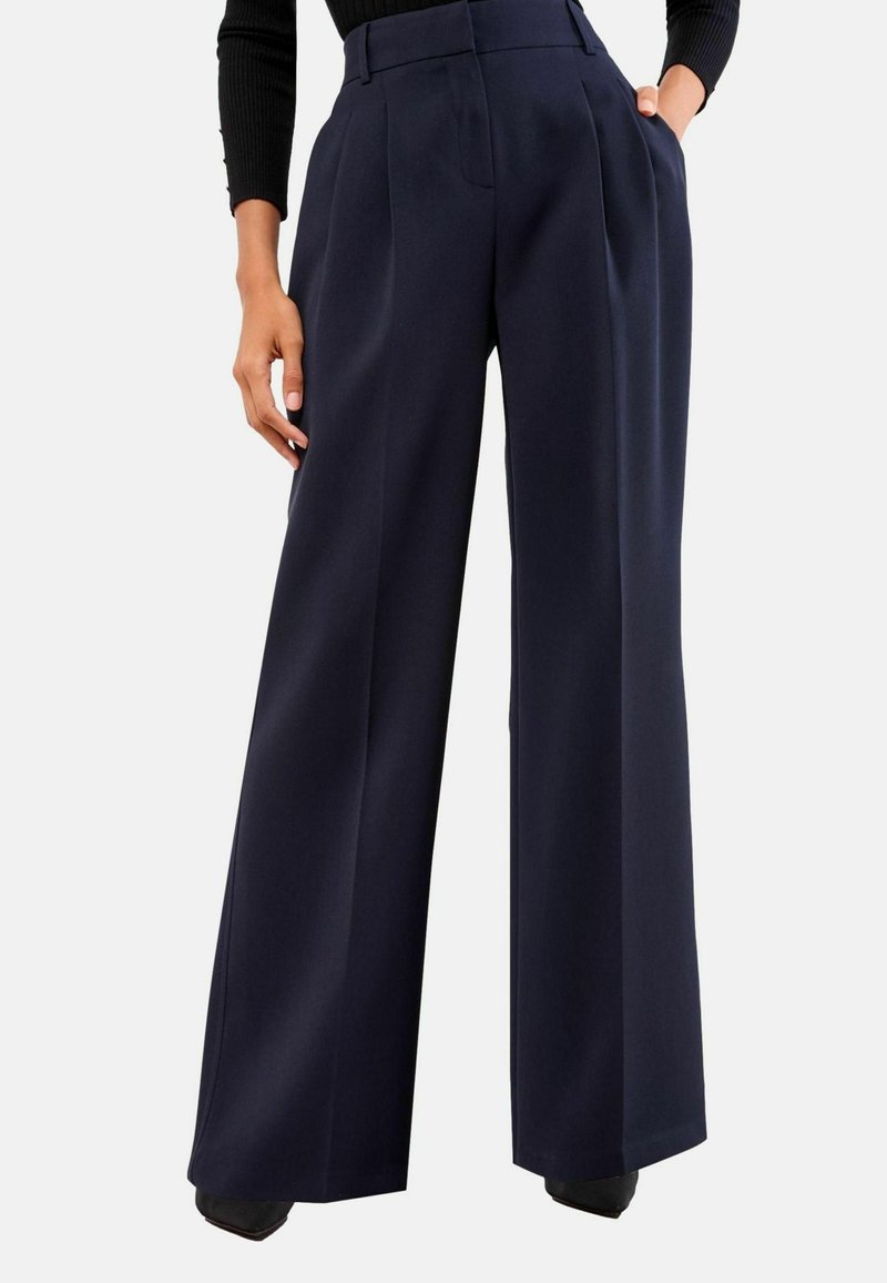 Wide-leg navy trousers with pleats, high waist, and pockets. Fabric appears smooth with a tailored fit and sharp creases.