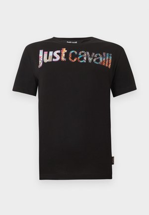 Melns īsroku T-krekls ar daudzkrāsainu rakstainu "just cavalli" logotipu uz krūtīm uz vienkrāsaina balta fona.