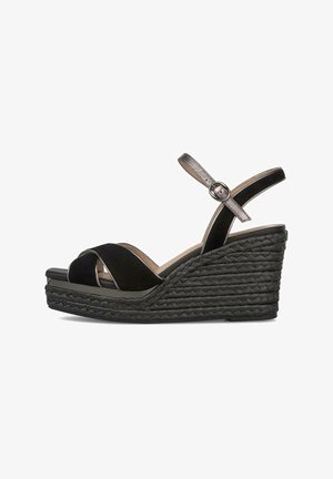 Sandalia negra de cuña con suela plataforma trenzada, tiras delanteras cruzadas y correa metálica en el tobillo con cierre de hebilla.