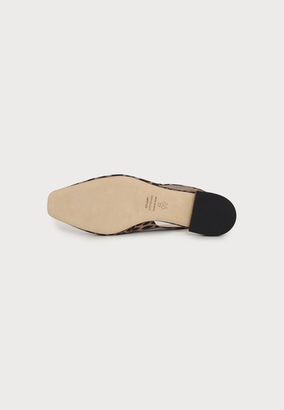 Chaussure plate avec semelle beige, talon noir et motif léopard visible autour du bord, vue par en dessous.