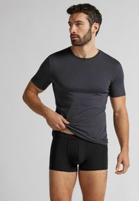 Koszulka z krótkim rękawem i okrągłym dekoltem w ciemnoszarym kolorze, zestawiona z dopasowanymi czarnymi slipami. Gładka tekstura i prosty design.