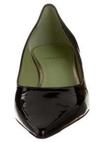 Černá lakovaná bota na vysokém podpatku s špičatou špičkou, zeleným vnitřním lemováním a zlatými doplňky. Má hladkou, lesklou strukturu.