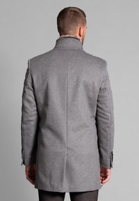 Abrigo de mezcla de lana gris con un corte entallado, cuello con muesca y detalle de botones en los puños. Presenta un acabado suave y texturizado. Vista trasera.