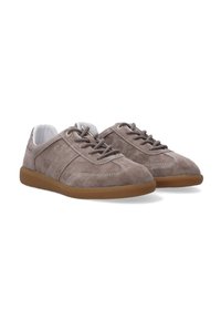 Bruine suède lage sneakers met bijpassende veters, witte voering, witte stiksels en zolen van rubber met een gumafwerking, zij aan zij weergegeven.
