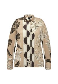 Chemisier à manches longues en tissu beige avec des motifs floraux et circulaires en noir et crème. Design avec col et fermeture par boutons.