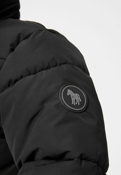 Melna pūkainā jakas ar apaļu zebras logo uzlīmi kreisajā piedurknē, ar gludu, spīdīgu virsmu un quiltētu tekstūru.