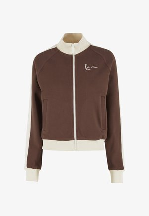 Brown zip-up jacket with a stand collar, white accents on sleeves, two front pockets, and a white logo embroidered on the chest.