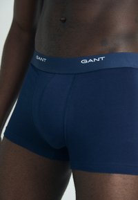 Marineblaue Boxershorts aus Baumwolle, mit einem einfarbigen Design und einem elastischen Bund mit der Markenbezeichnung "GANT" in weißer Schrift.