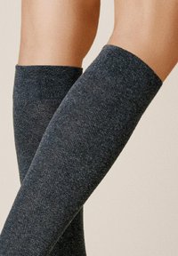 Kniestrümpfe in dunkelgrau, mit geripptem Muster und glatter Oberfläche, ausgestattet mit einem breiten oberen Bündchen für einen enganliegenden Sitz und einem subtilen Glanz.