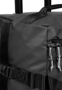 Zwarte reistas met een textuurafwerking, voorzien van dubbele ritsen met trekkoorden, verstelbare banden en een stevige draaghandgreep.