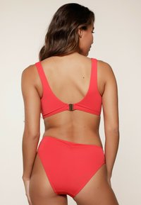 Rood bikiniset met een lage rugontwerp, brede banden en verstelbare haaksluiting. Gladde textuur met minimale stikdetails.