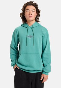 Turquoise hoodie made of soft fabric, featuring a front kangaroo pocket, drawstrings, and a diamond logo on the chest.